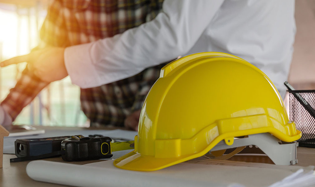 yellow safety helmet on workplace desk with construction worker yellow safety helmet on workplace desk with construction worker